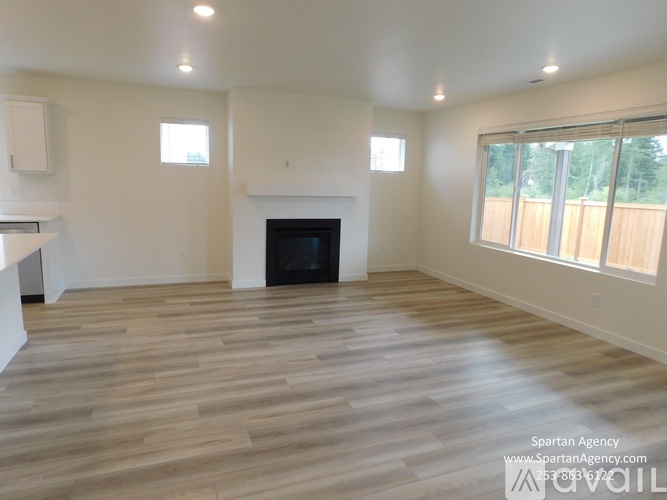 A large, empty room with wood flooring and a fireplace.