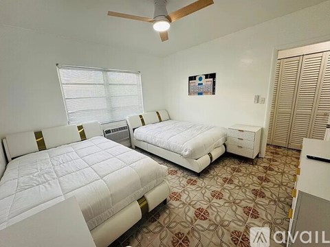 A bedroom with two beds and a ceiling fan.