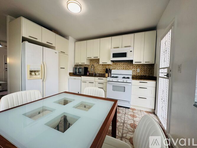 A kitchen with white cabinets and a glass table.