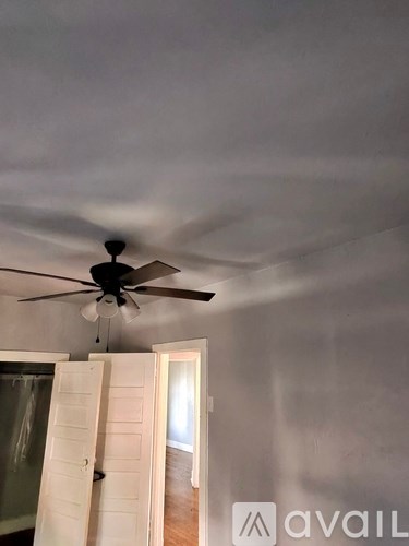 A room with a ceiling fan and a window with a curtain.