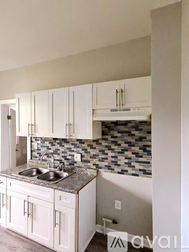 A kitchen with white cabinets and a tiled backsplash.