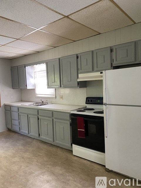 A kitchen with a white refrigerator and grey cabinets.