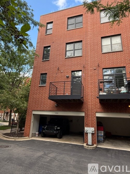 A red brick building with a black car in the garage.