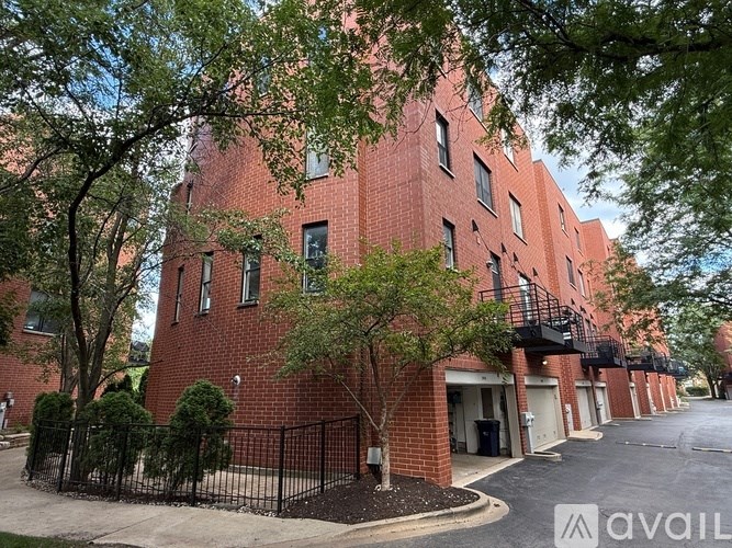 A red brick building with a black fence and trees in front.