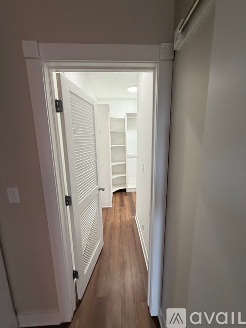 A hallway with a white door and a wooden floor.