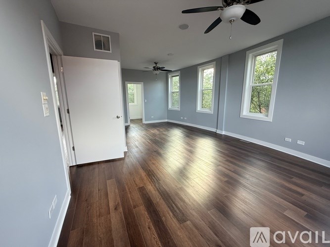 A spacious room with wood flooring and a ceiling fan.