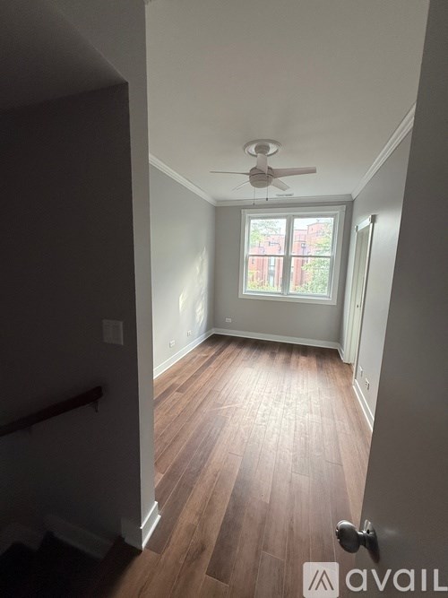 A room with a ceiling fan and wooden flooring.
