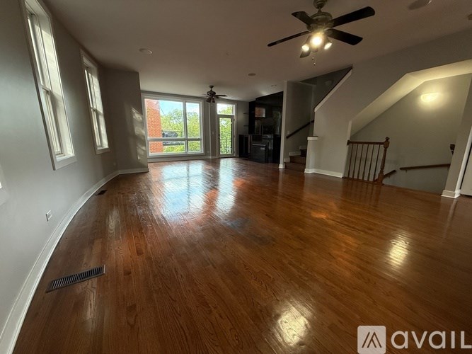 A spacious room with wooden floors and a ceiling fan.