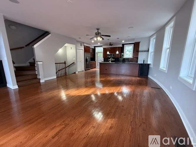 A spacious room with wooden flooring and a ceiling fan.