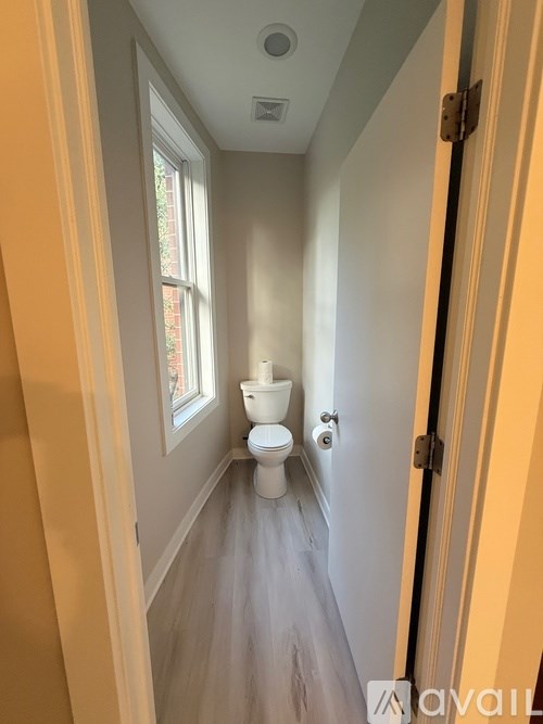 A bathroom with a toilet and a window.