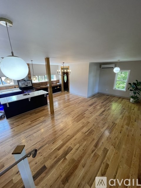 A room with wooden flooring and a large white lamp hanging from the ceiling.