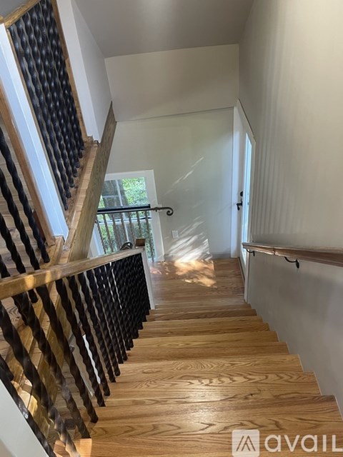 A wooden staircase with a black railing.