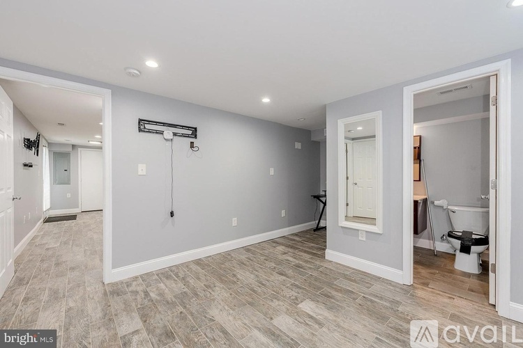 A spacious room with a toilet and a sink visible through the open door.