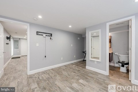 A spacious room with a toilet and a sink visible through the open door.