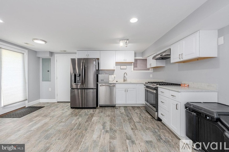 A modern kitchen with white cabinets and a wooden floor.