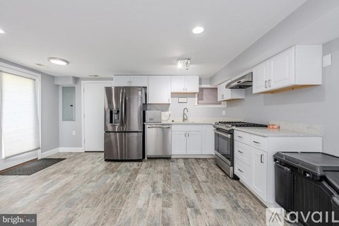 A modern kitchen with white cabinets and a wooden floor.