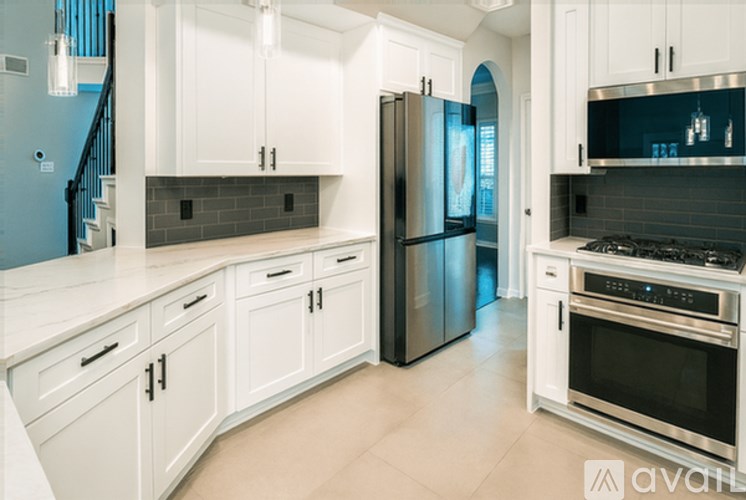 A kitchen with white cabinets and a black refrigerator.