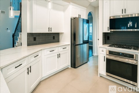 A kitchen with white cabinets and a black refrigerator.
