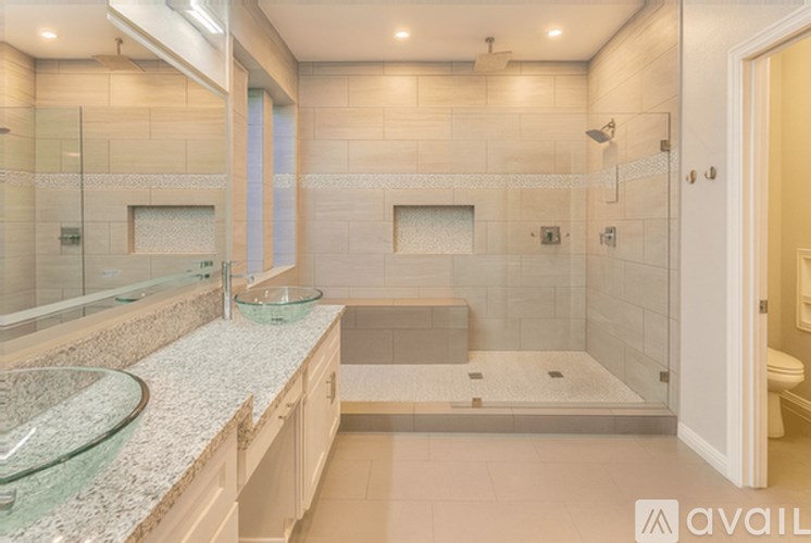 A bathroom with a glass shower door and a glass sink.
