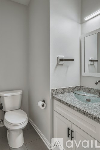 A bathroom with a toilet, sink and mirror.