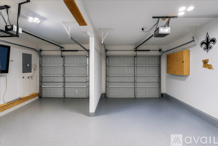 A spacious garage with two grey garage doors and a wooden cabinet on the wall.