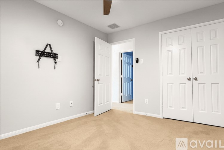 A room with a white door and a black shelf on the wall.