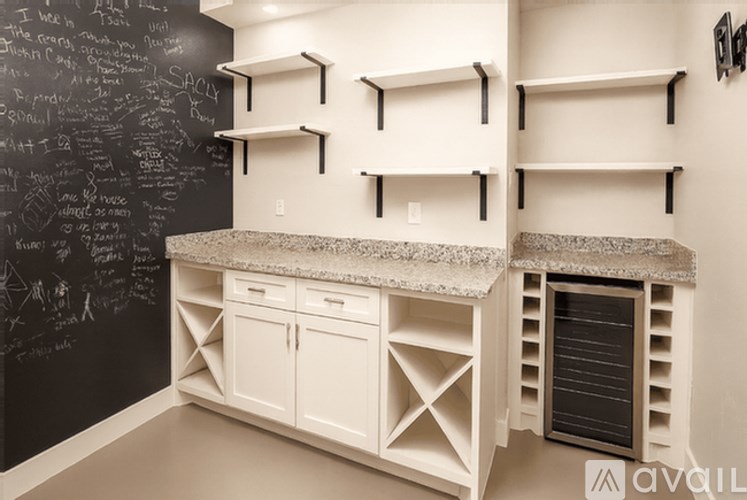 A kitchen with a chalkboard wall and white cabinets.