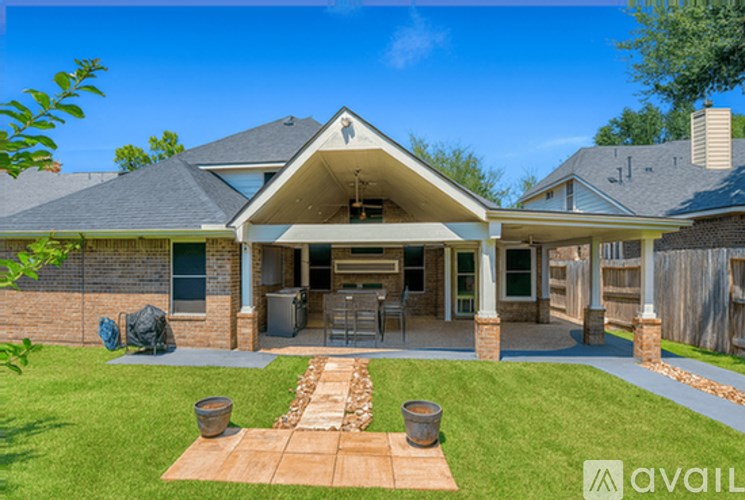 A house with a covered patio and a stone fireplace.