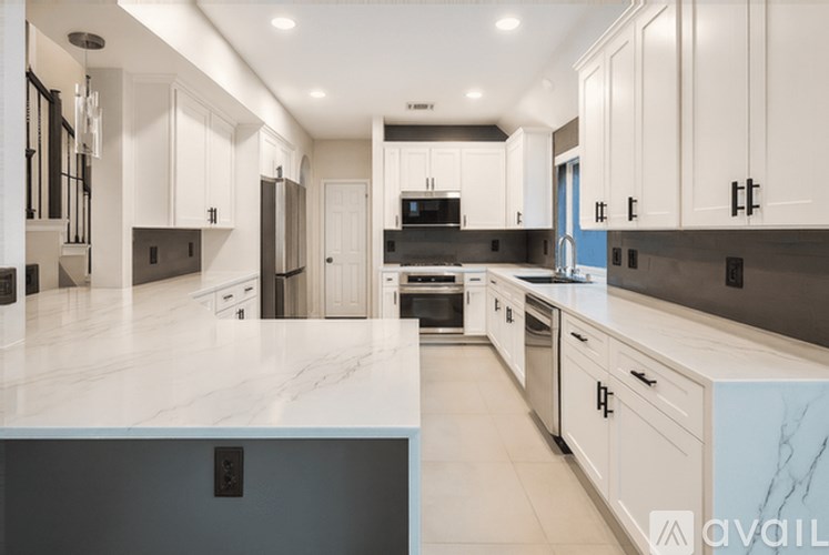 A modern kitchen with white cabinets and a marble countertop.