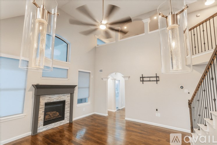 A spacious living room with a fireplace and a ceiling fan.