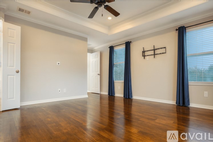 A spacious room with a ceiling fan and hardwood floors.