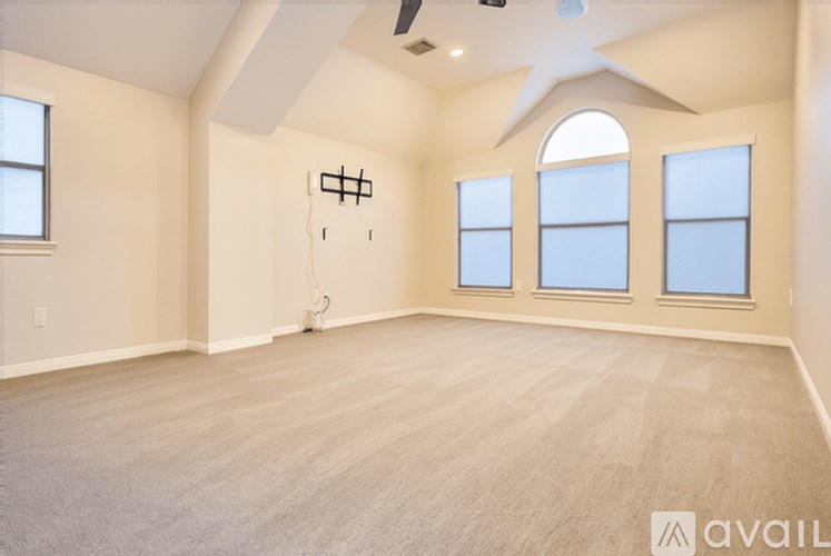 A spacious room with a fan and three windows.