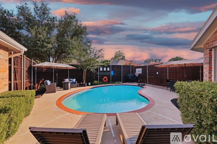 A backyard with a pool and a basketball hoop.