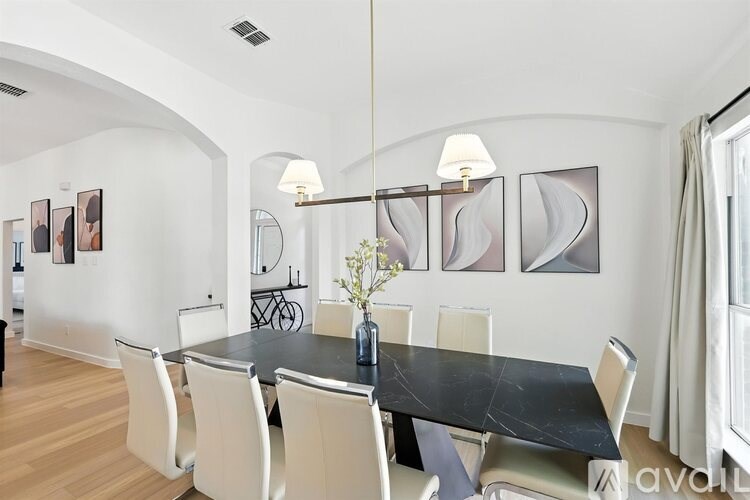 A modern dining room with a black table and white chairs.