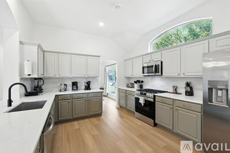 A modern kitchen with wooden floors and stainless steel appliances.