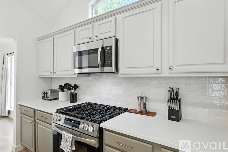 A kitchen with a black stove top and white cabinets.