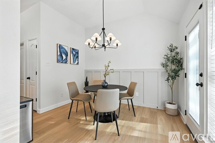 A dining room with a table set for two and a plant on the side table.