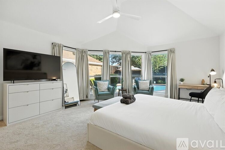 A bedroom with a large bed, a television, and a sliding glass door leading to a pool.