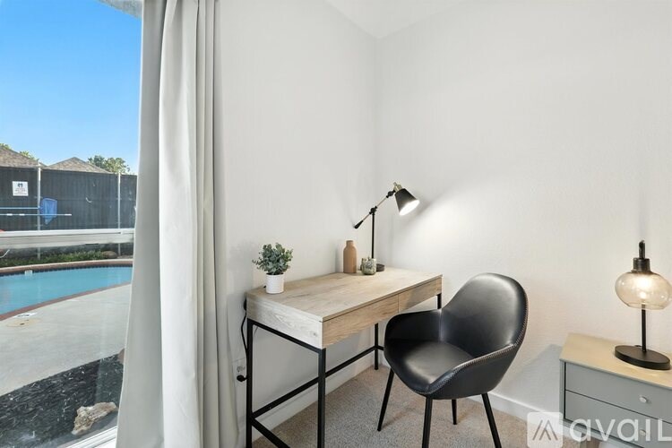 A room with a desk, chair, and lamp.