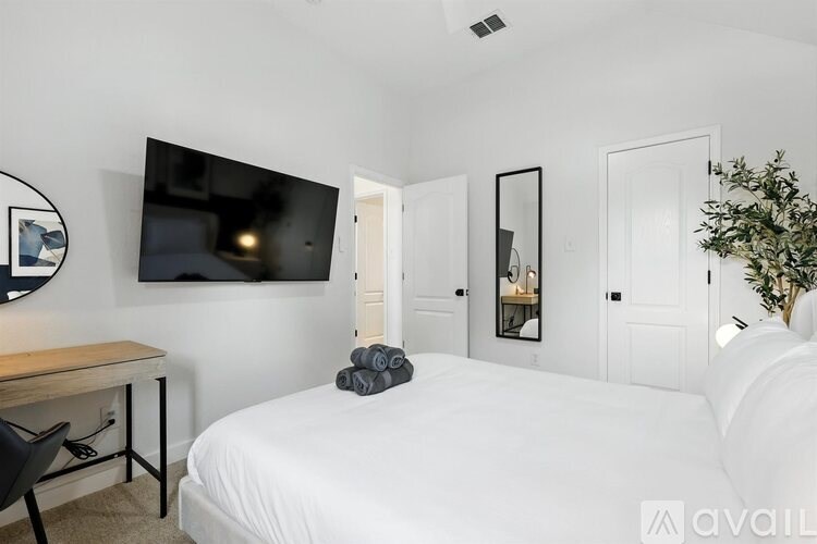 A bedroom with a bed, desk, and mirror.