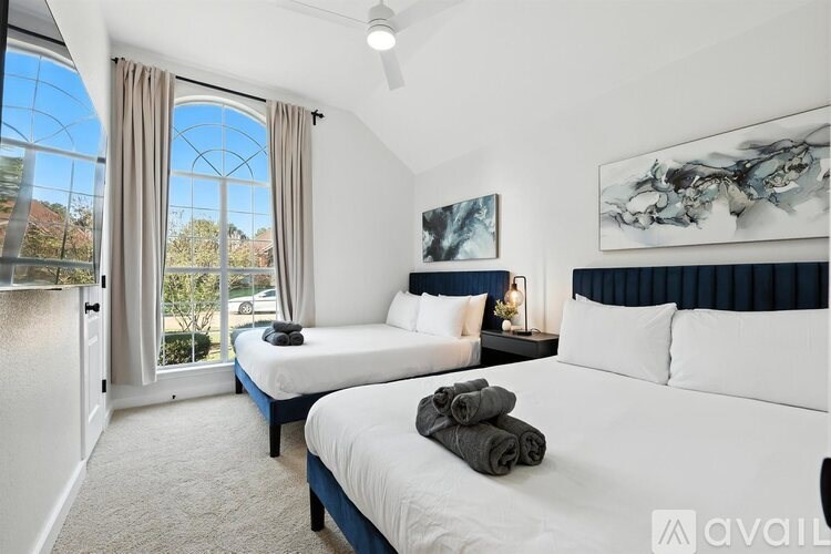 A bedroom with two beds, one with towels on top, and a ceiling fan.