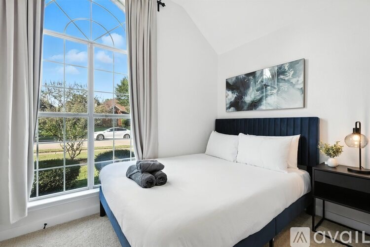 A bedroom with a large bed and a window overlooking a garden.