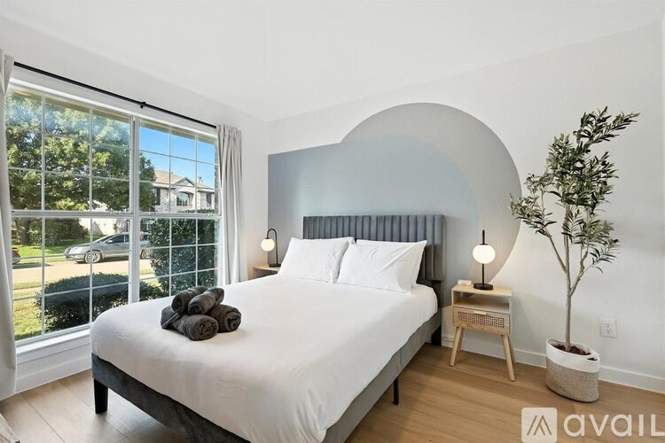 A bedroom with a large bed and a window overlooking a street.