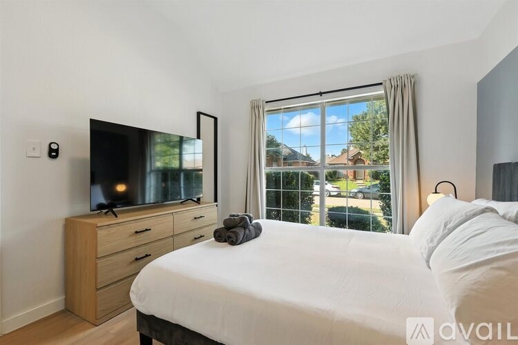 A bedroom with a bed, dresser, and a television.