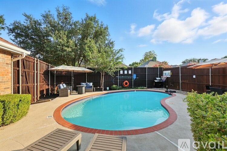 A pool surrounded by a wooden fence and a basketball hoop.