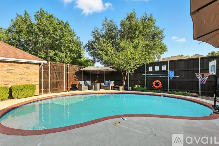 A pool surrounded by a black fence and a brown umbrella.
