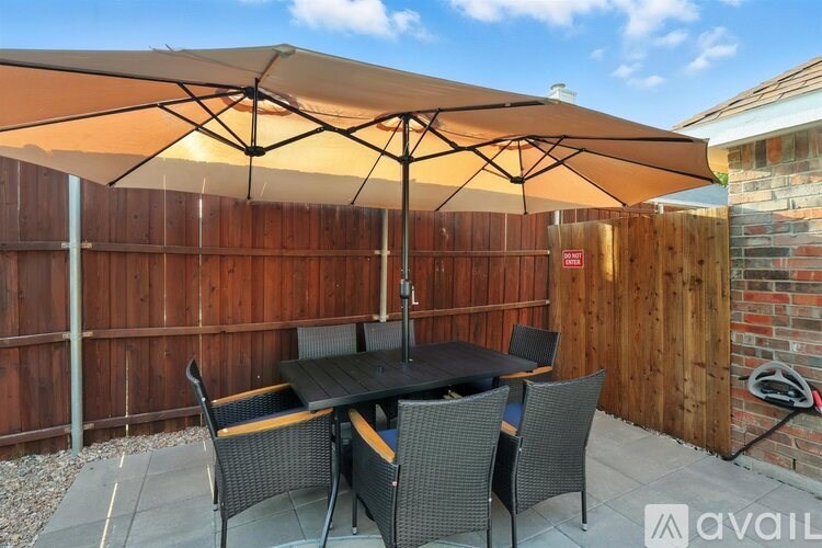 A patio with a table and chairs under an umbrella.