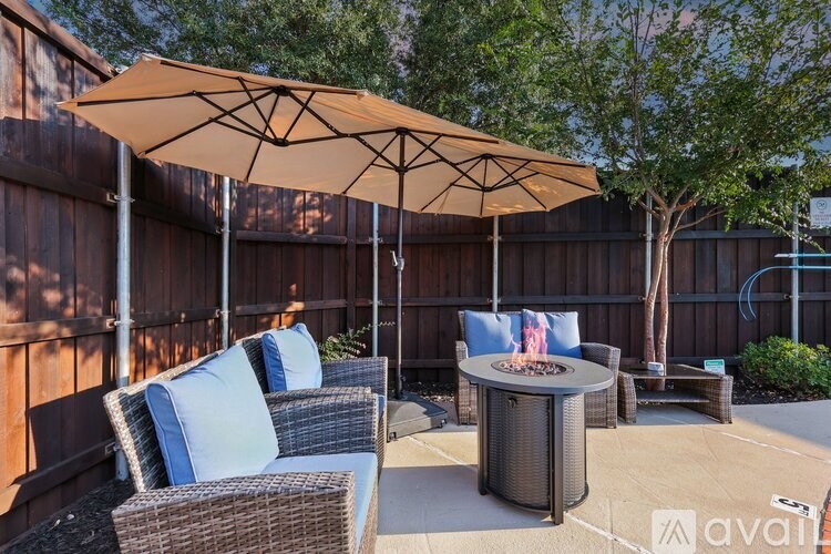 A patio with a table, chairs, and an umbrella.
