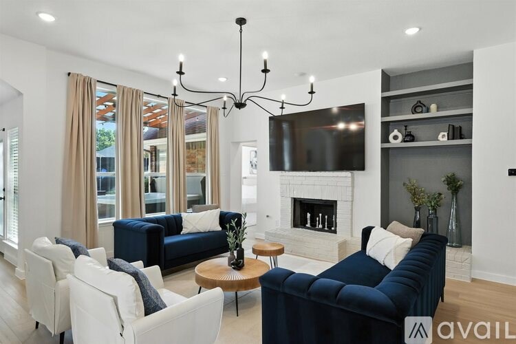 A living room with a dark blue sofa and white chairs.