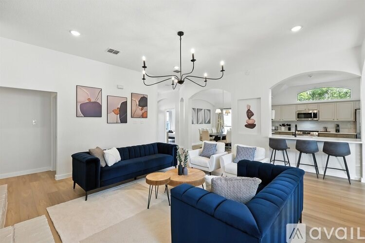 A living room with a blue couch and a chandelier.
